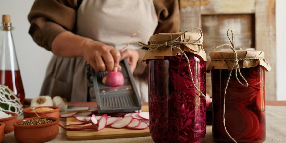 Person using glass jars and containers while preparing vegetables in a kitchen
