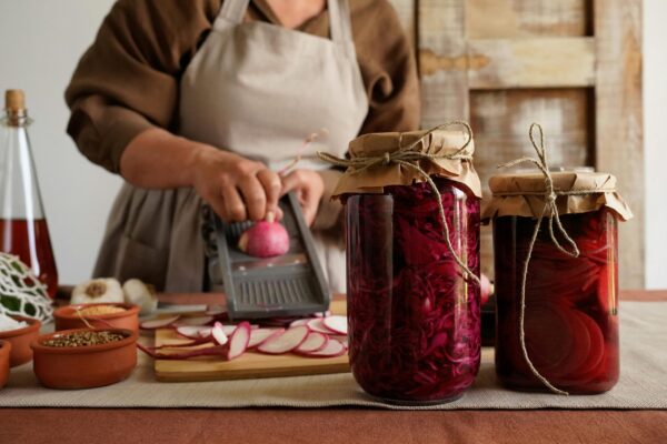 Person using glass jars and containers while preparing vegetables in a kitchen