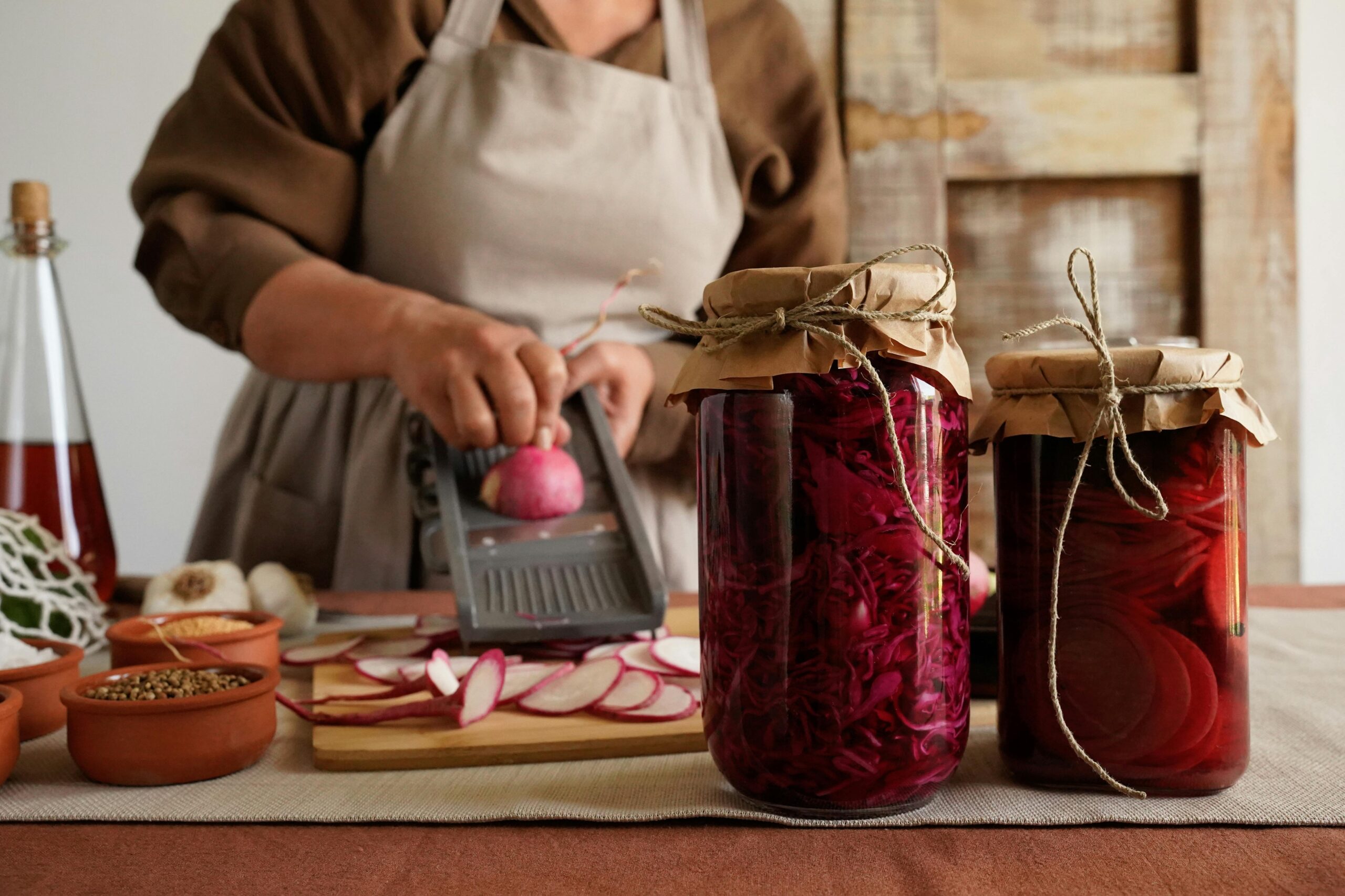 Person using glass jars and containers while preparing vegetables in a kitchen