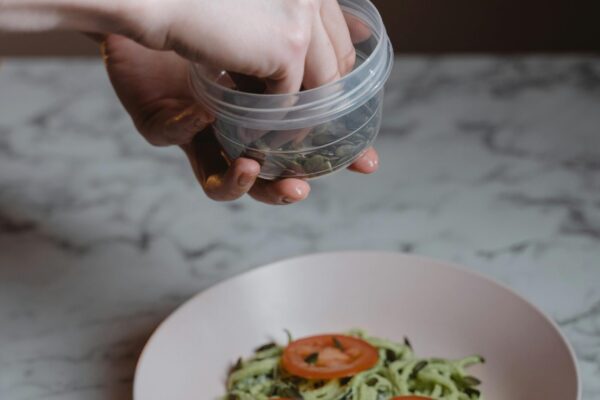 Person holding and using a plastic food container while preparing a healthy meal